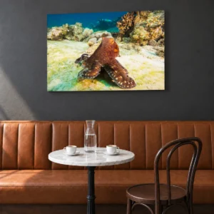 Large octopus and diver canvas, 36 × 24 in (91 × 61 cm), above a restaurant banquette, with cups and a water carafe on a round table